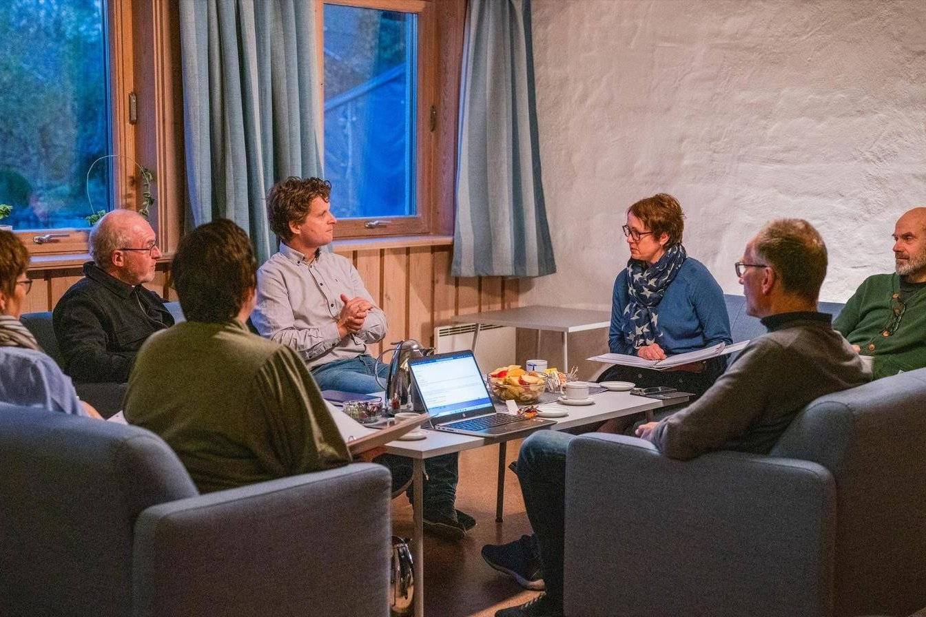 Syv personer sitter i en sofagruppe og snakker. Foto: Torstein Kiserud