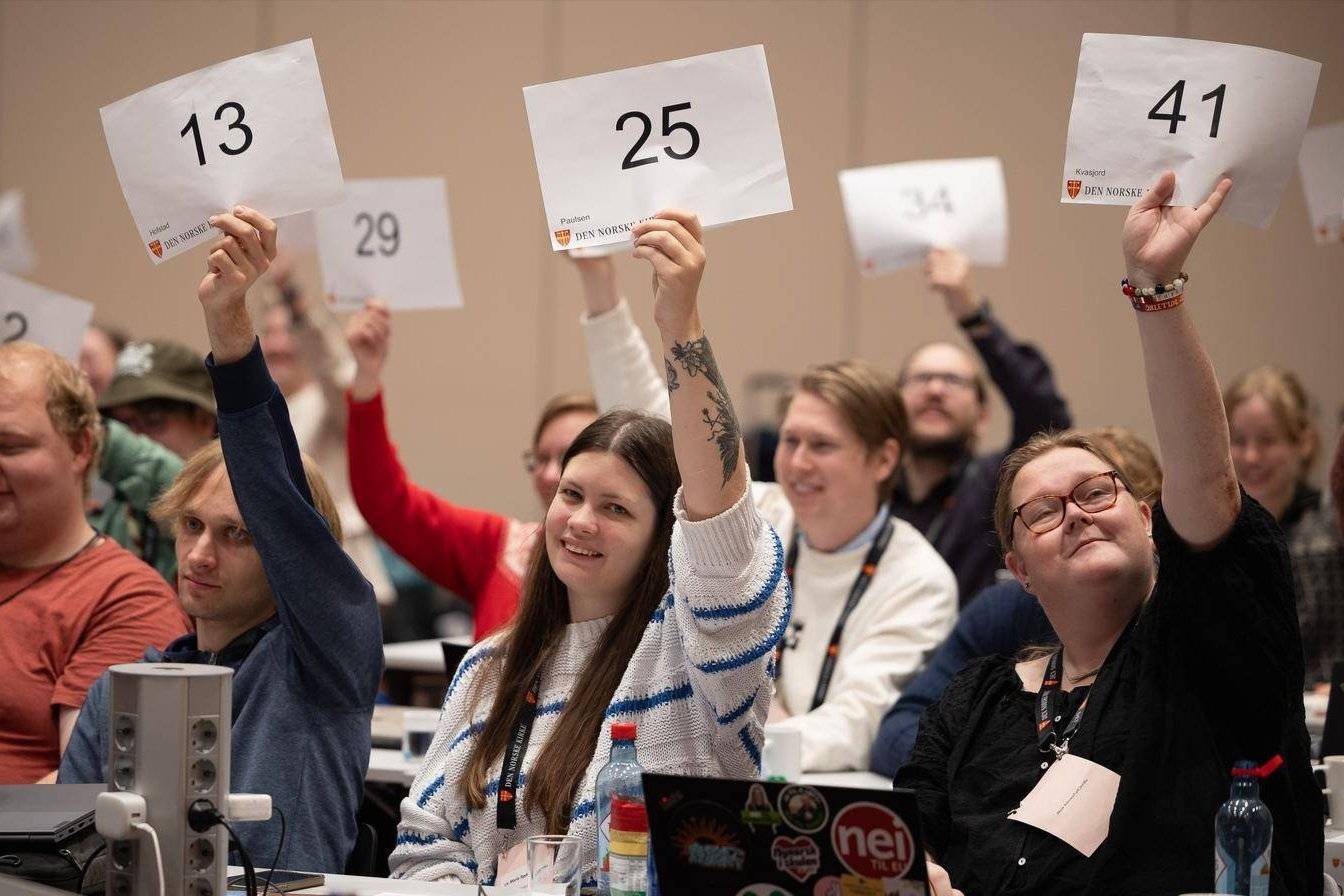 Bilde av ungdommer som løfter stemmesedlene på Ungdommens kirkemøte.