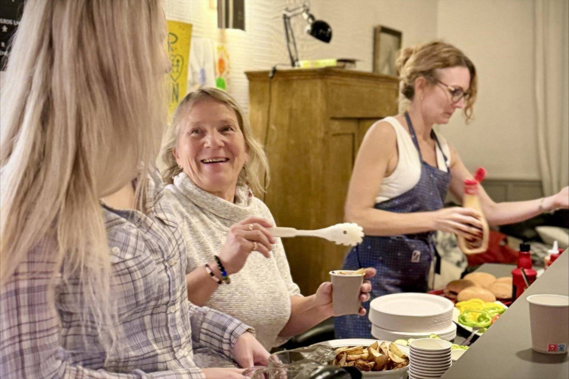 Tre frivillige serverer mat.